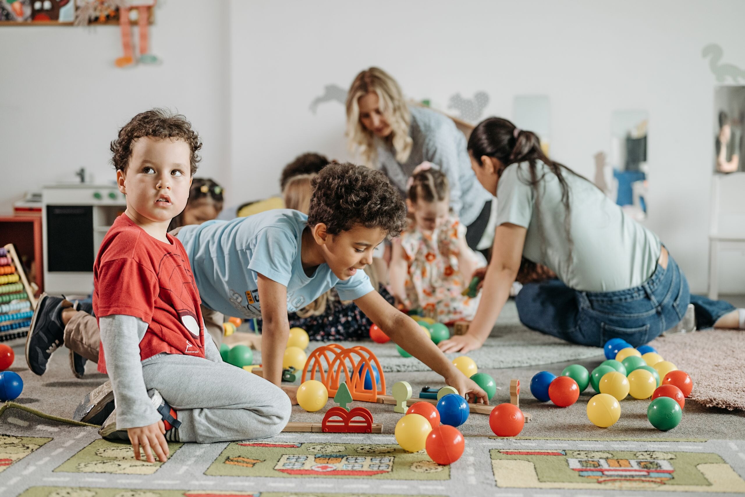 Pedagogisch medewerker speelt met peuters met ballen